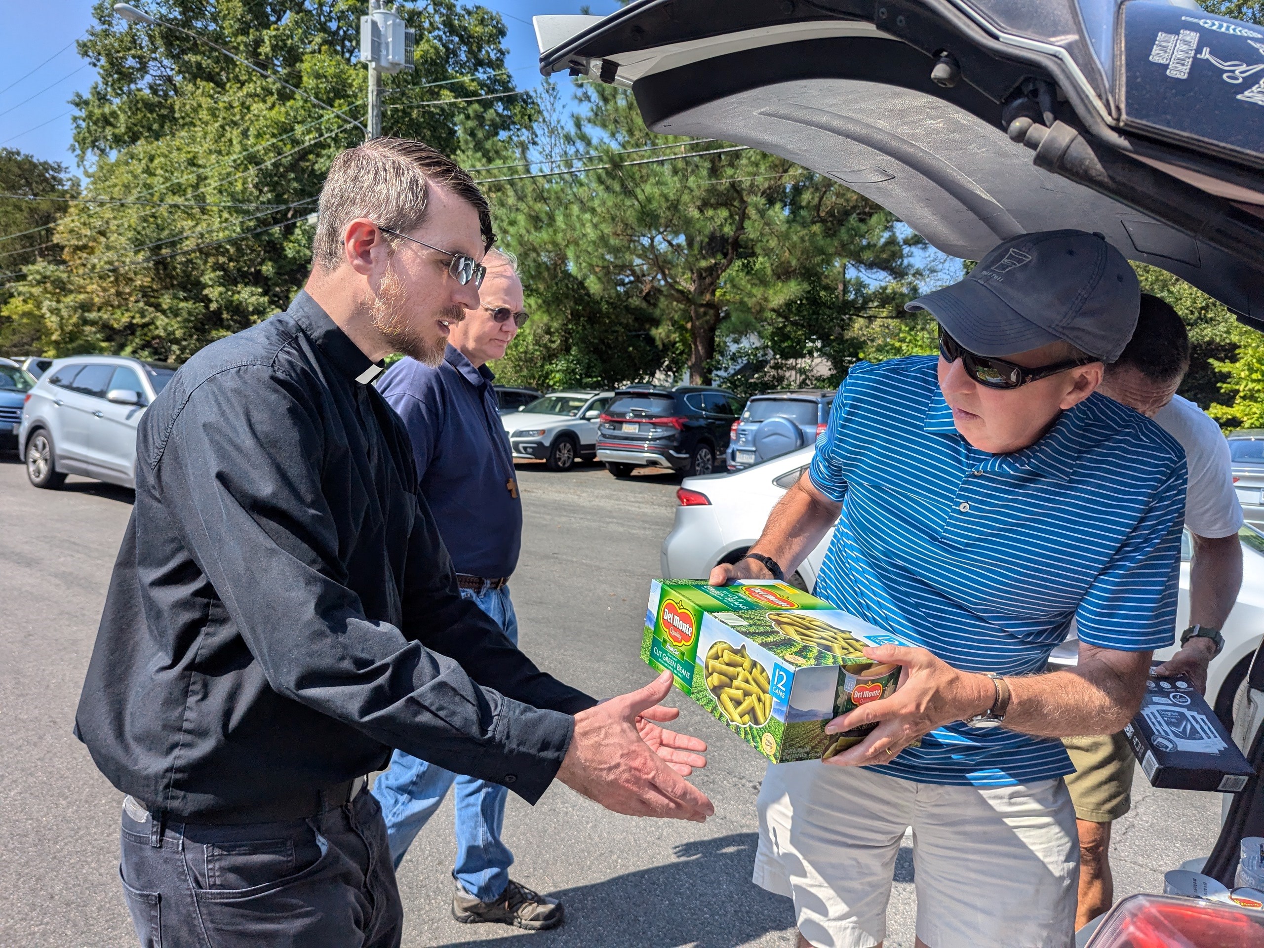 Parishioner Peter Mahoney and son John hand off food contributions to Fr. Seth and Fr. Ken.